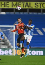 Tom Lockyer heads the ball clear under pressure from Brahima Diarra