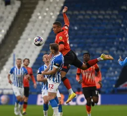 Carlton Morris leaps above Tom Lees