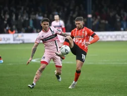 Jordan Clark controls the ball under pressure from Gavan Holohan