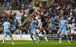 Ben Wilson punches the ball away from Tom Lockyer`s head