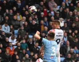 Carlton Morris rises above Callum Doyle to head the ball forward