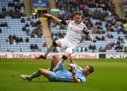 Alfie Doughty trys to ride Callum Doyle`s sliding tackle