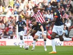 Jordan Clark has the ball at his feet as Pierre Ekwah appears to jump on top of him