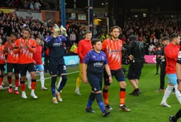 Tom Lockyer along with a mascot lead the team onto the field