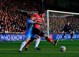 Tom Lockyer is being held by Joe Gelhardt as he trys to reach the ball