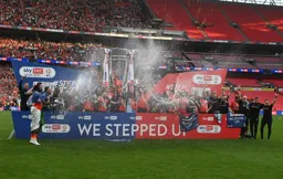 Sonny Bradley holds the trophy aloft as the champagne rains down