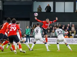 Carlton Morris head the ball across the penalty area