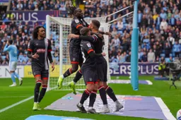 Carlton Morris is mobbed after scoring from the penalty spot