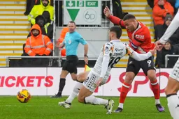 Carlton Morris plays the ball past Xavier Simons