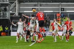 Carlton Morris rises above Lewie Coyle to direct a header towards goal