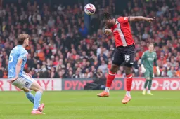 Teden Mengi heads the ball powerfully forward