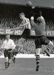 Bernard Streten rises to punch the ball watched by Wally Shanks